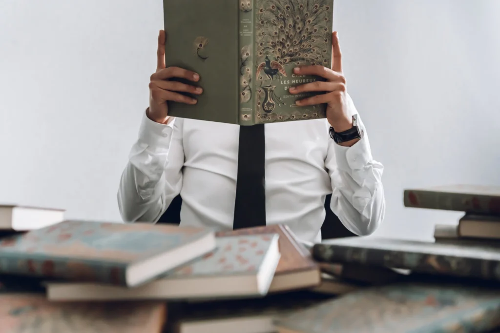 Homme lisant des livres sur son bureau dans un cadre sobre – Stan Agency, spécialiste de la ligne éditoriale et des stratégies de contenu